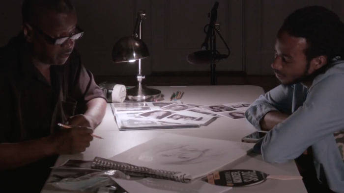 Two men sitting at a table looking at sketch drawings