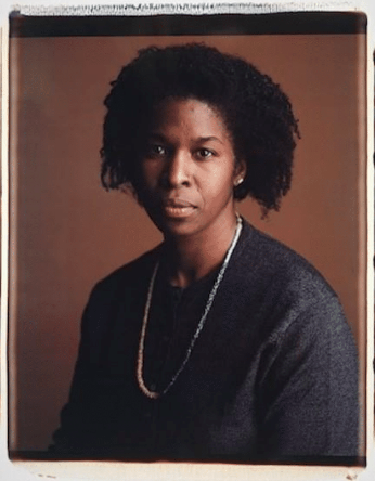 Portrait of black woman wearing a grey top and gold chain necklace