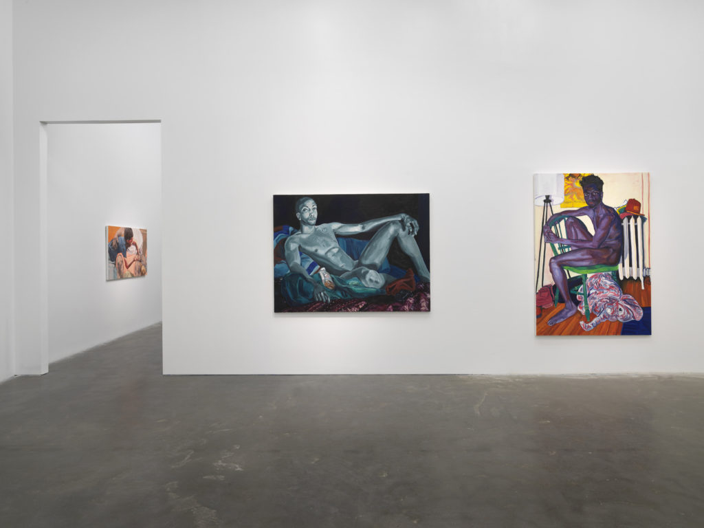 An installation view of an exhibition, with two paintings on a wall and a third visible through a doorway